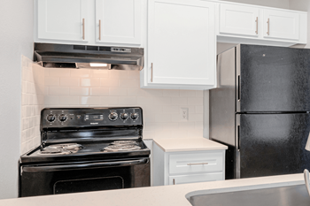 A kitchen with white cabinets and a black stove and refrigerator